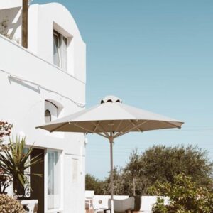 Peaceful outdoor terrace in Santorini with umbrella and lush greenery. Ideal vacation spot.